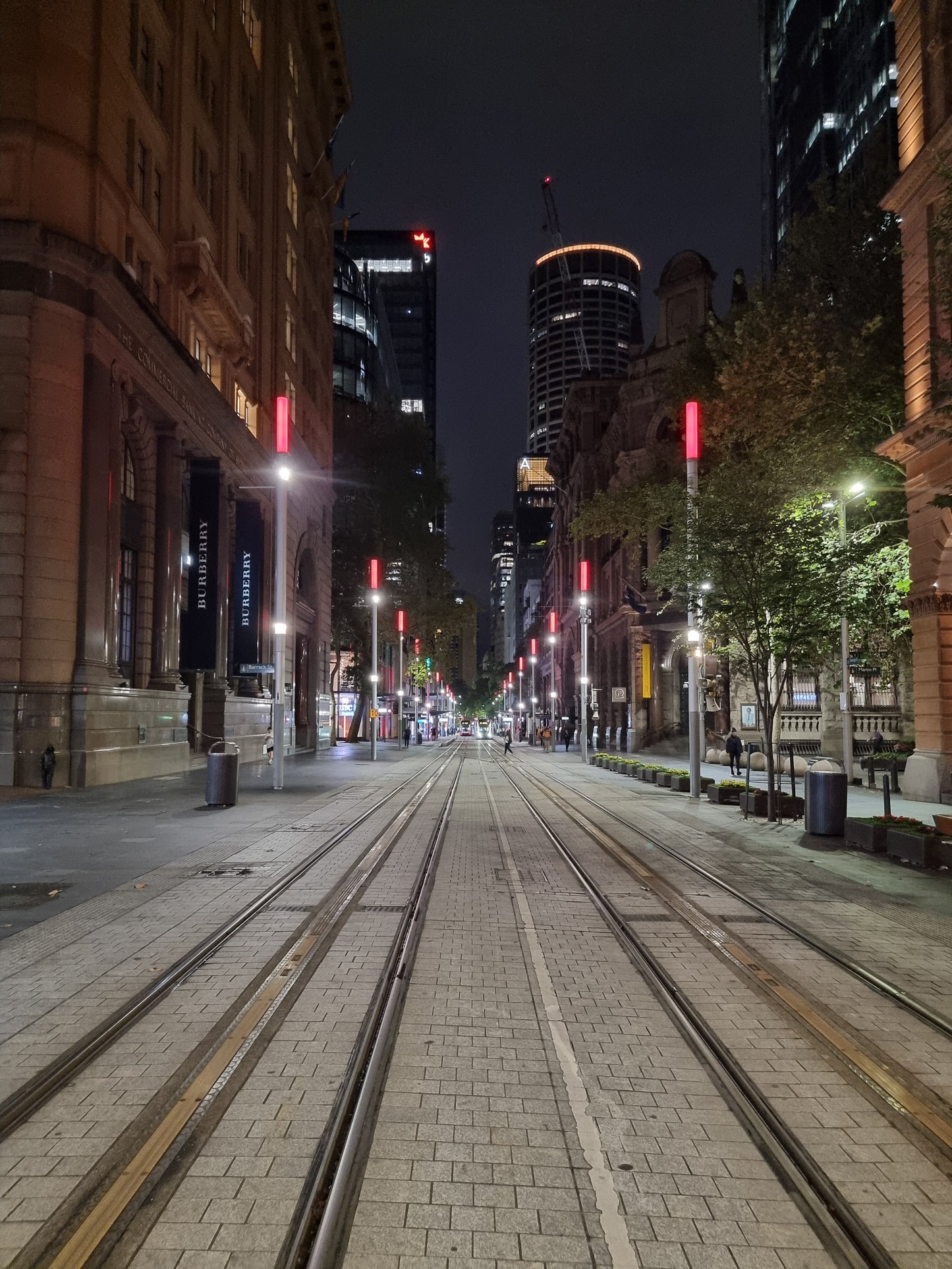 Light post topped with red neon lights along the tram lines of George St, Sydney. Pre-dawn colour photo.
