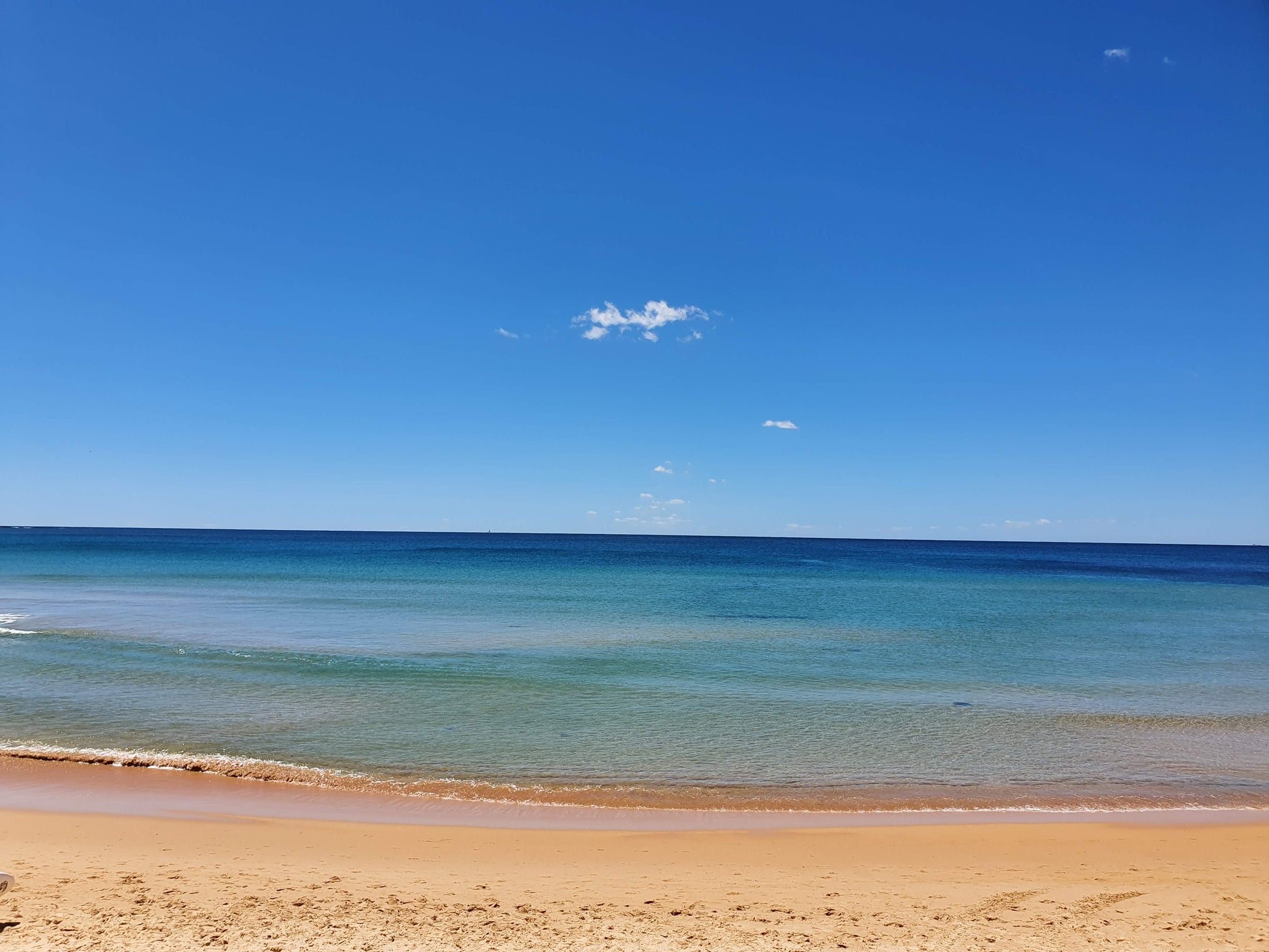 Dee Why Beach. Burnished summer sand. Crystal waters, flat as a lagoon. The blue of the ocean blends to the sky.