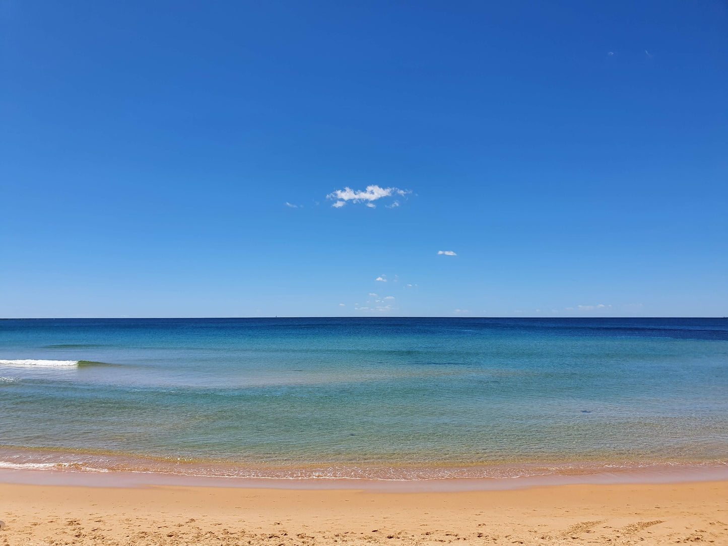 Tranquil waters at Dee Why beach, with the blues reaching to the sky on the horizon.