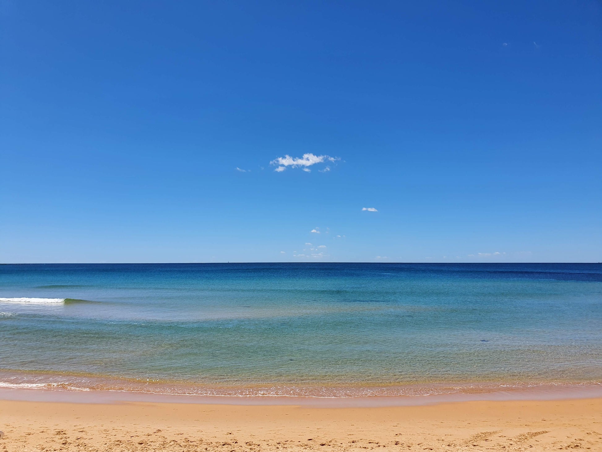 Tranquil waters at Dee Why beach, with the blues reaching to the sky on the horizon.